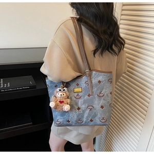 Detail of grey canvas tote bag with brown embroidery and a cute teddy bear charm