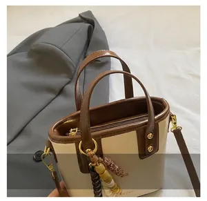 Détail d'un sac seau bicolore avec pendentif en perles et bandoulière amovible