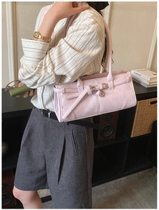 Chic light pink leather crossbody bag with silver buckle worn by a model in a casual setting