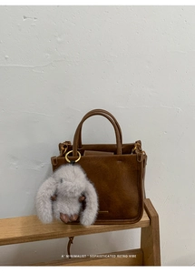 Detail of retro brown leather bucket bag with a cute fluffy rabbit charm on handle