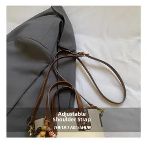 Gros plan sur la bandoulière réglable et les finitions dorées du sac seau bicolore
