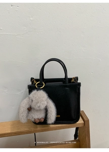 Detail of black retro handbag with leather texture and cute grey bunny pendant