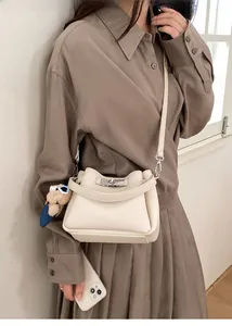 Détail du sac à main en cuir grainé blanc cassé avec fermoir argenté et breloque ours