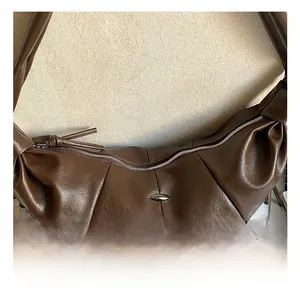 Detailed view of the dark brown croissant bag with pleated texture and silver hardware