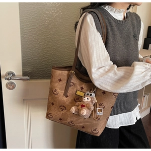 Close-up of brown vintage monogram tote bag with leather strap and cute bear charm
