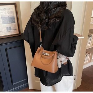 Close-up of brown litchi pattern leather bucket bag with metal buckle and rabbit charm