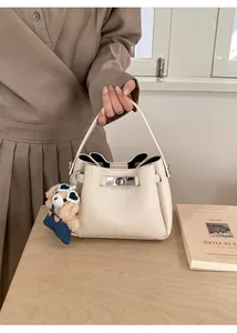 Détail du sac seau en cuir grainé blanc cassé avec un charmant pendentif d'ours brun