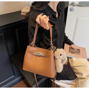 Detail of brown litchi pattern leather bucket bag with silver clasp and plush rabbit charm