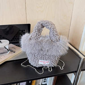 Detail of grey plush faux fur tote bag with metallic bead chain and woven text label