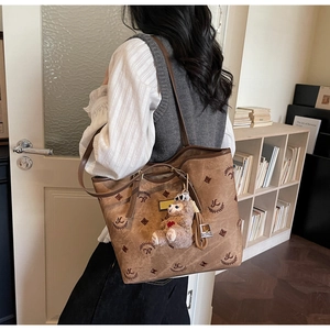 Close-up of brown suede tote bag with pattern print and cute plush bear charm