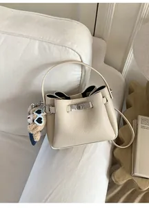 Détail du sac seau en cuir grainé blanc cassé avec fermoir argenté et breloque ours