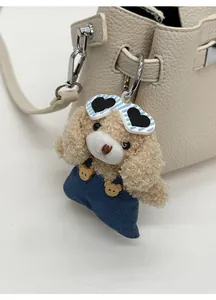 Gros plan d'un charme de sac ours en peluche avec lunettes sur un sac en cuir blanc