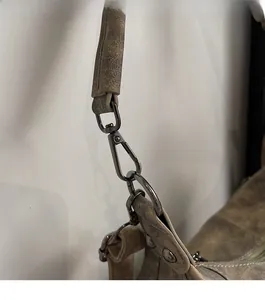 Détail de la texture cuir vintage et quincaillerie robuste en métal foncé avec fermoir