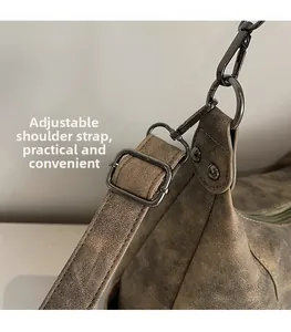 Gros plan de la bandoulière réglable avec boucles en métal foncé sur sac vintage brun