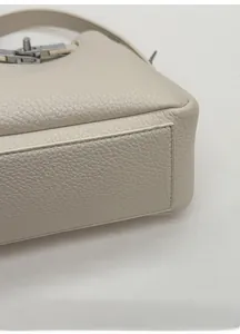 Vue détaillée de la base renforcée et du fermoir rotatif en argent du sac seau beige