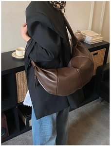 Detail of deep brown faux leather croissant bag showing soft texture and wide strap