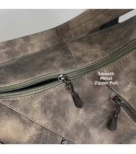 Détail des fermetures éclair en métal et du cuir vintage texturé d'un sac à bandoulière brun