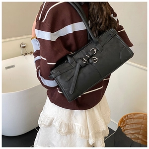 Detail of a black rectangular shoulder bag with silver ring buckles on a shoulder strap