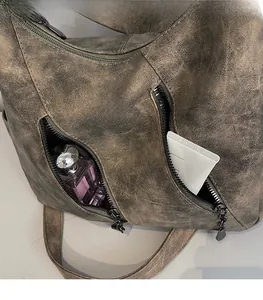 Gros plan des poches zippées sur un sac bandoulière vintage avec démonstration de rangement