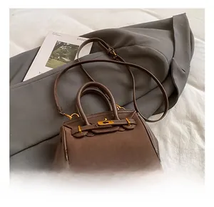 Detailed macro view of a brown pebbled leather handbag with golden turn-lock closure