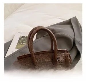 Detail of lychee pattern leather handbag with metallic buckle and sturdy top handles