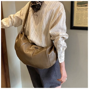 Detail of olive brown pleated crescent crossbody bag with oval metal decoration