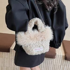 Detail of beige fuzzy handbag with plush trim and metal chain strap on model