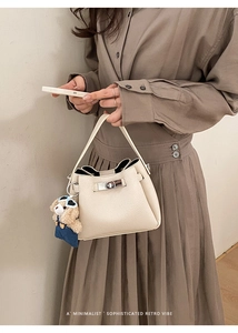 Détail du sac seau en cuir crème avec fermoir argenté et breloque ours en peluche