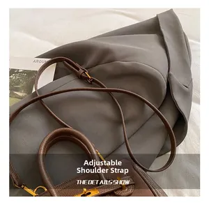 Detail showing the adjustable thin leather shoulder strap and golden metal buckle of the bag