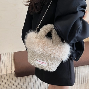 Detail of white plush crossbody bag with red text embroidery and silver metal chain strap