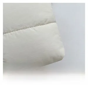 Macro detail of white quilted padded fabric with premium stitching and soft texture