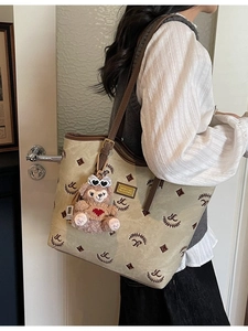 Fashionable beige canvas tote bag with brown leather trim and cute bear charm