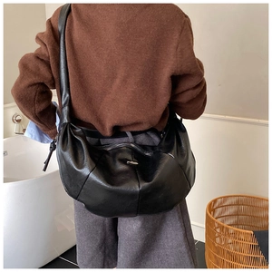 Close-up of black hobo bag with silver zipper and leather texture on a shoulder