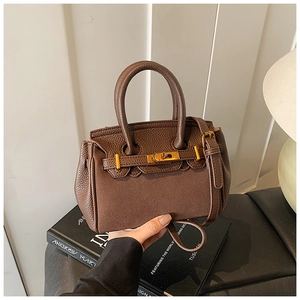 Detail of dark brown lychee textured leather bag with gold twist lock and flip cover
