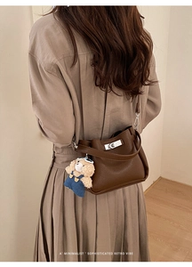 Gros plan du sac seau marron foncé avec boucle et charmant pendentif d'ours en peluche