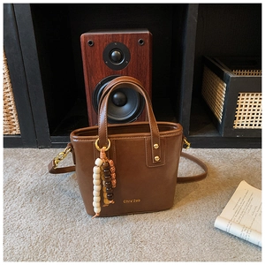 Detail of vintage brown PU leather bucket bag with retro wooden bead charm and gold logo