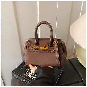 Close-up of brown lychee grain leather handbag with vintage gold twist-lock closure