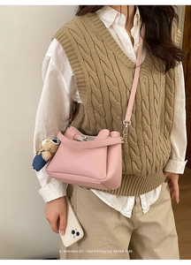 Détail du sac seau rétro rose avec fermoir en métal et breloque ours sur un modèle