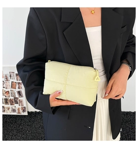 Primer plano del bolso de nailon acolchado amarillo claro con tirador de cremallera triangular
