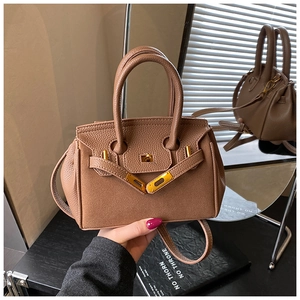 Close-up of brown litchi grain leather handbag with iconic golden metal lock and strap