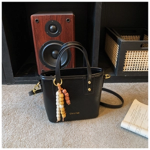 Detail of black leather bucket bag with vintage beads and gold hardware accents