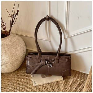 Detail of dark brown vintage rectangle handbag with decorative buckle belt on a magazine