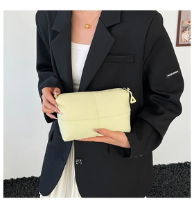 Macro detail of quilted cream yellow clutch bag with soft texture and triangle zipper puller