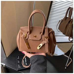 Detail of classic brown lychee texture handbag with golden hardware and rotating lock