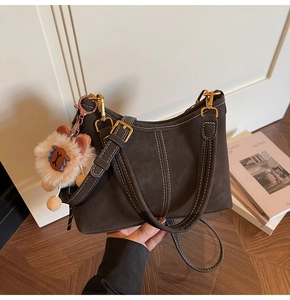 Detail of dark brown bucket bag with white contrast stitching and plush animal charm
