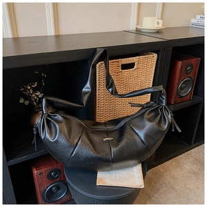 Detail of black crescent hobo bag featuring pleated leather and charcoal metal hardware
