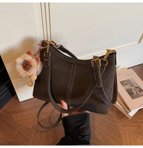 Detail of dark brown vintage bucket bag with white stitching and cute animal charm