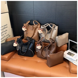 Detailed view of large litchi grain leather tote bags set with plush bear pendant charm