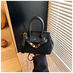 Close-up of black lychee grain leather handbag with gold hardware and top handle design