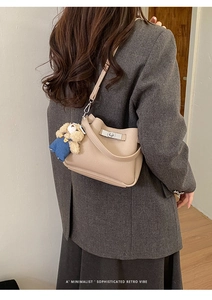 Détail du sac seau en cuir beige avec fermoir rotatif argenté et breloque petit ours